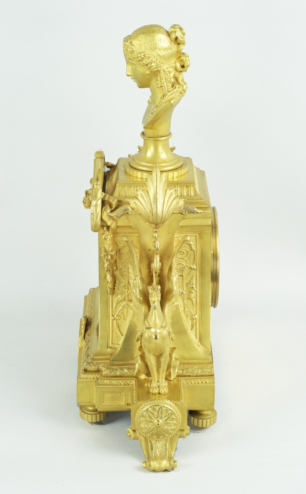 A French ormolu mantel clock featuring a classical female bust finial, blue enamel dial, and flanked by winged griffins on an ornate base. View XIII