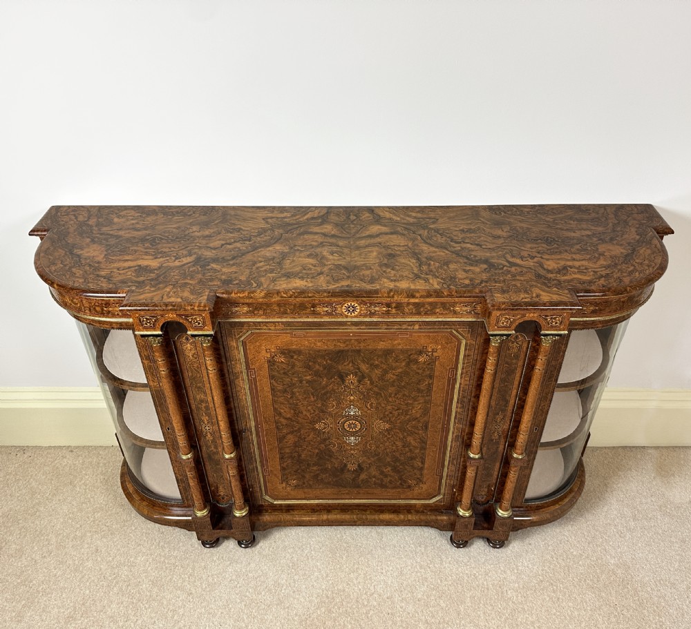 A Victorian burr walnut credenza sideboard featuring intricate marquetry inlay, a central panelled cupboard door, two curved glass display doors, and gilt brass mounts. View V