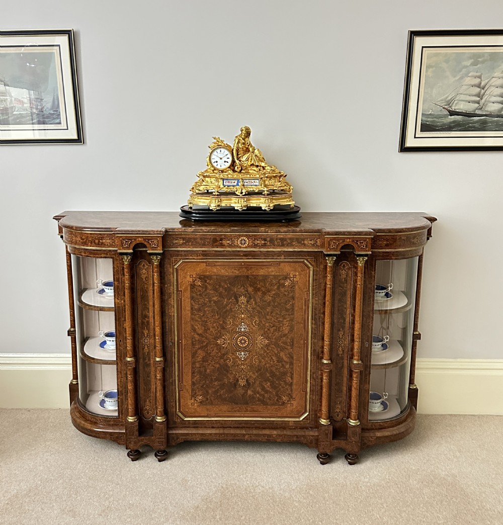 A Victorian burr walnut credenza sideboard featuring intricate marquetry inlay, a central panelled cupboard door, two curved glass display doors, and gilt brass mounts. View VI