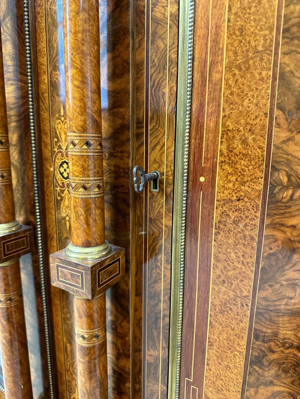 A Victorian burr walnut credenza sideboard featuring intricate marquetry inlay, a central panelled cupboard door, two curved glass display doors, and gilt brass mounts. View XI