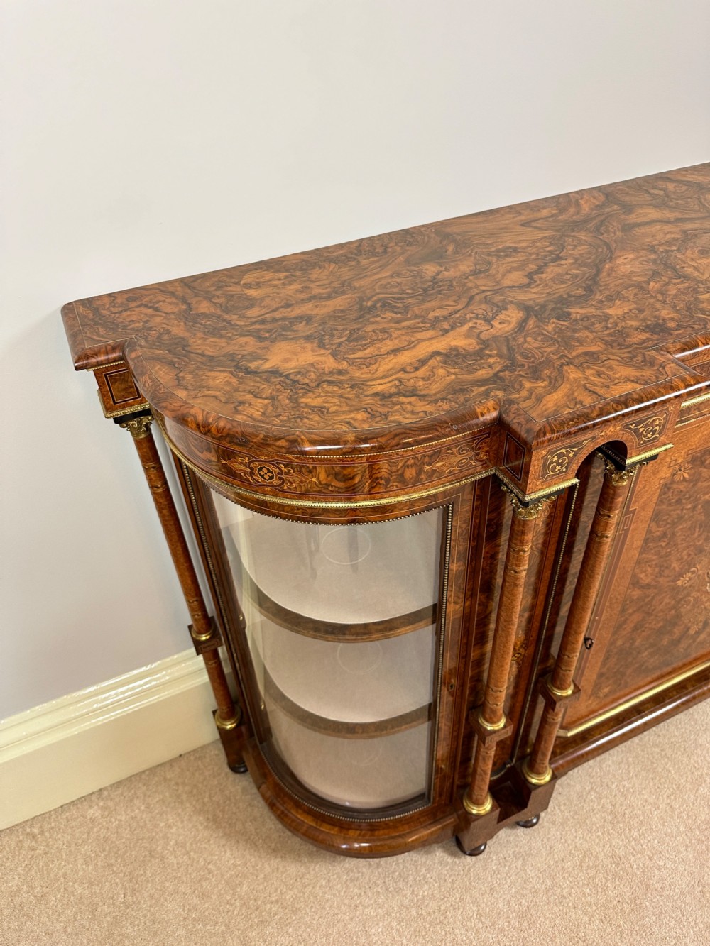 A Victorian burr walnut credenza sideboard featuring intricate marquetry inlay, a central panelled cupboard door, two curved glass display doors, and gilt brass mounts. View XII
