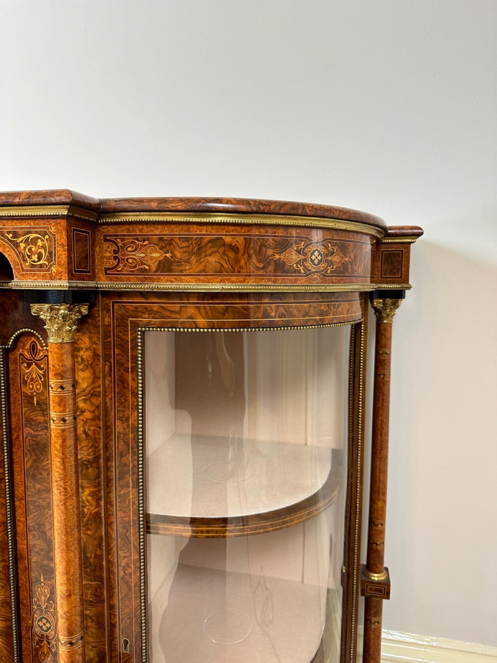 A Victorian burr walnut credenza sideboard featuring intricate marquetry inlay, a central panelled cupboard door, two curved glass display doors, and gilt brass mounts. View XIII