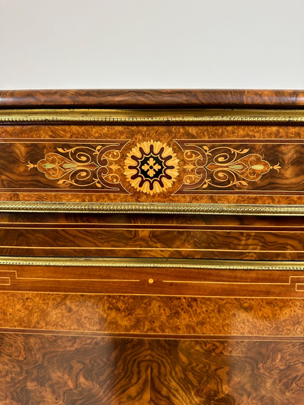 A Victorian burr walnut credenza sideboard featuring intricate marquetry inlay, a central panelled cupboard door, two curved glass display doors, and gilt brass mounts. View XVI