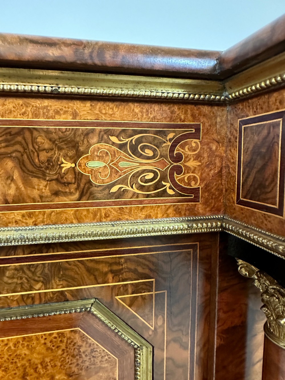 A Victorian burr walnut credenza sideboard featuring intricate marquetry inlay, a central panelled cupboard door, two curved glass display doors, and gilt brass mounts. View XVII