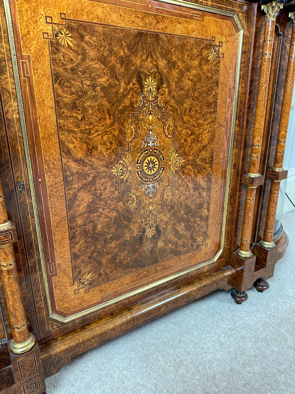 A Victorian burr walnut credenza sideboard featuring intricate marquetry inlay, a central panelled cupboard door, two curved glass display doors, and gilt brass mounts. View XVIII