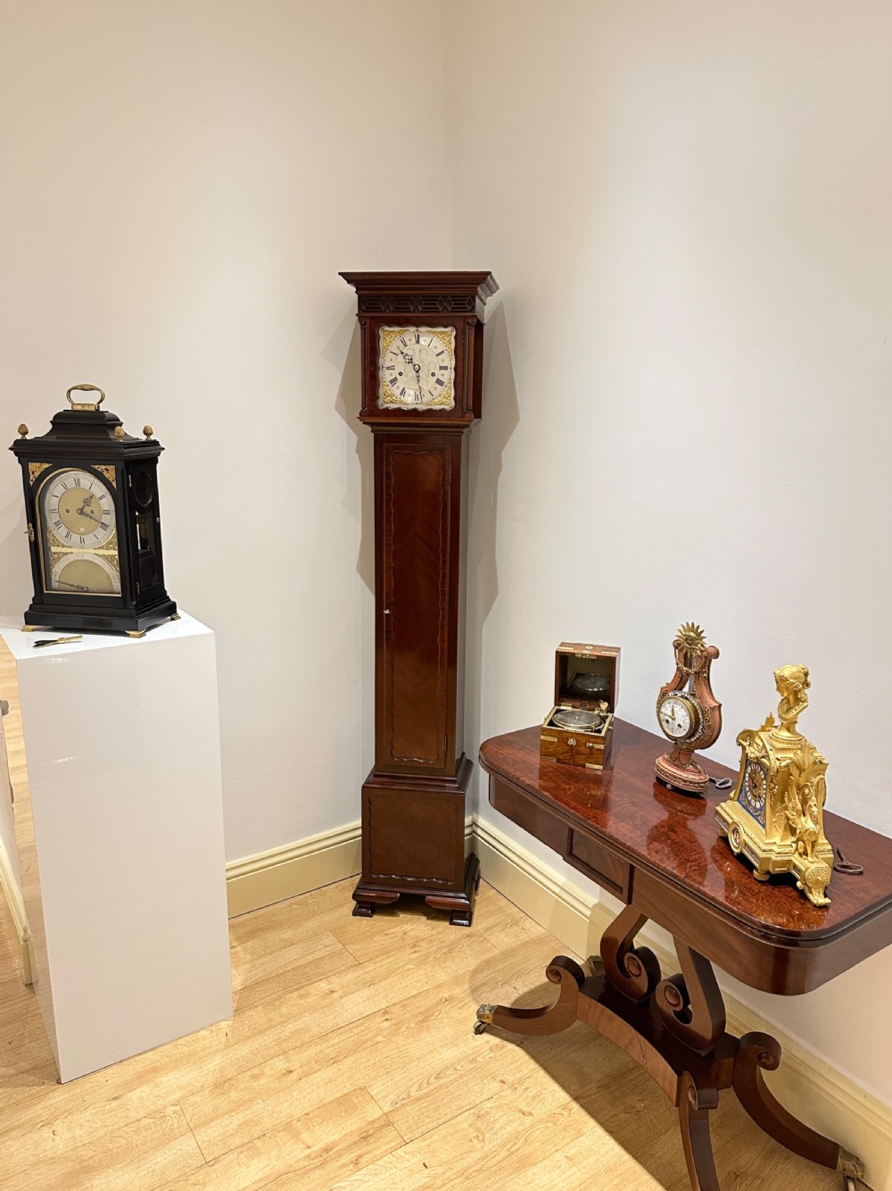 A tall mahogany grandmother clock featuring a brass and silvered dial with Roman numerals, geometric carved mouldings, and bracket feet. View II