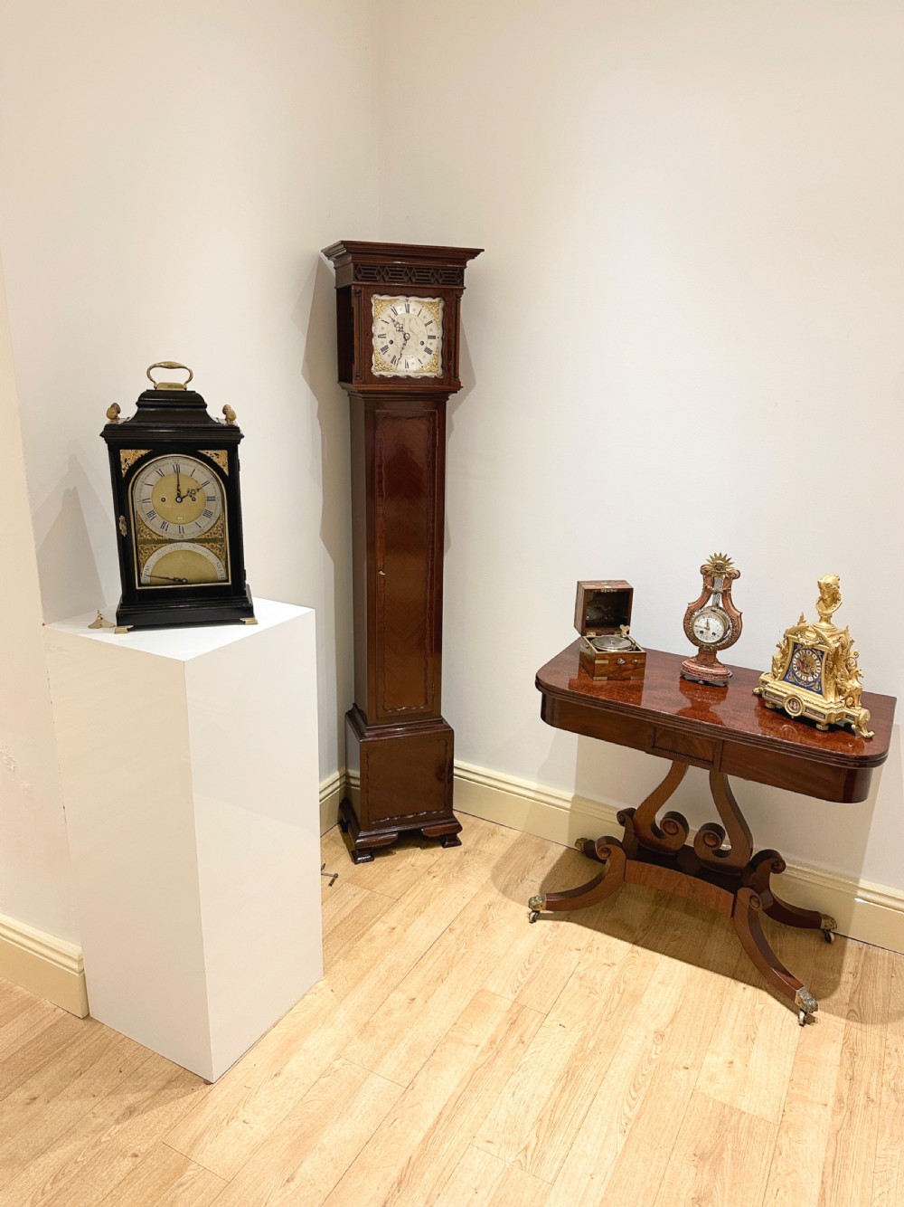 A tall mahogany grandmother clock featuring a brass and silvered dial with Roman numerals, geometric carved mouldings, and bracket feet. View III