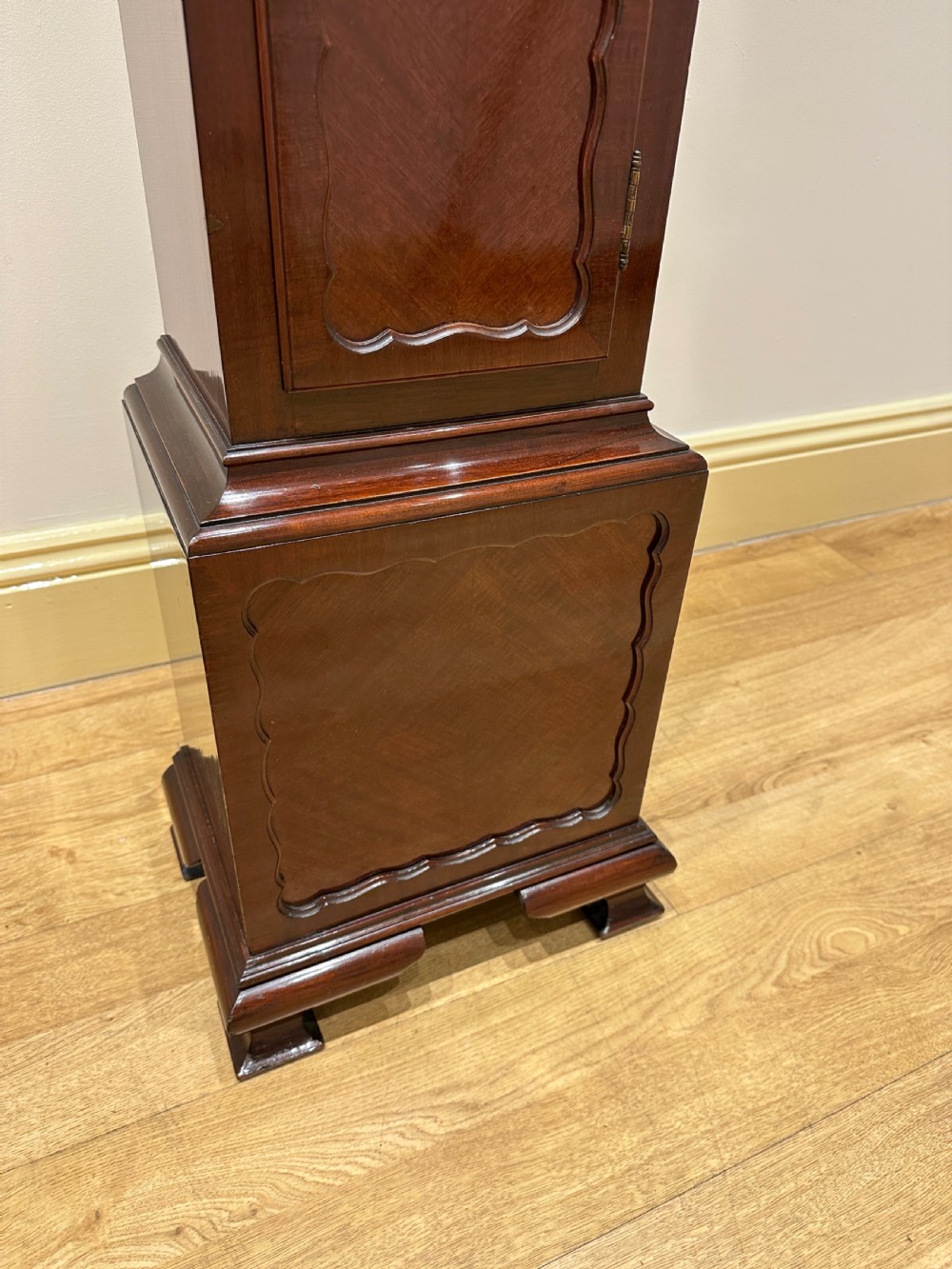 A tall mahogany grandmother clock featuring a brass and silvered dial with Roman numerals, geometric carved mouldings, and bracket feet. View XIV