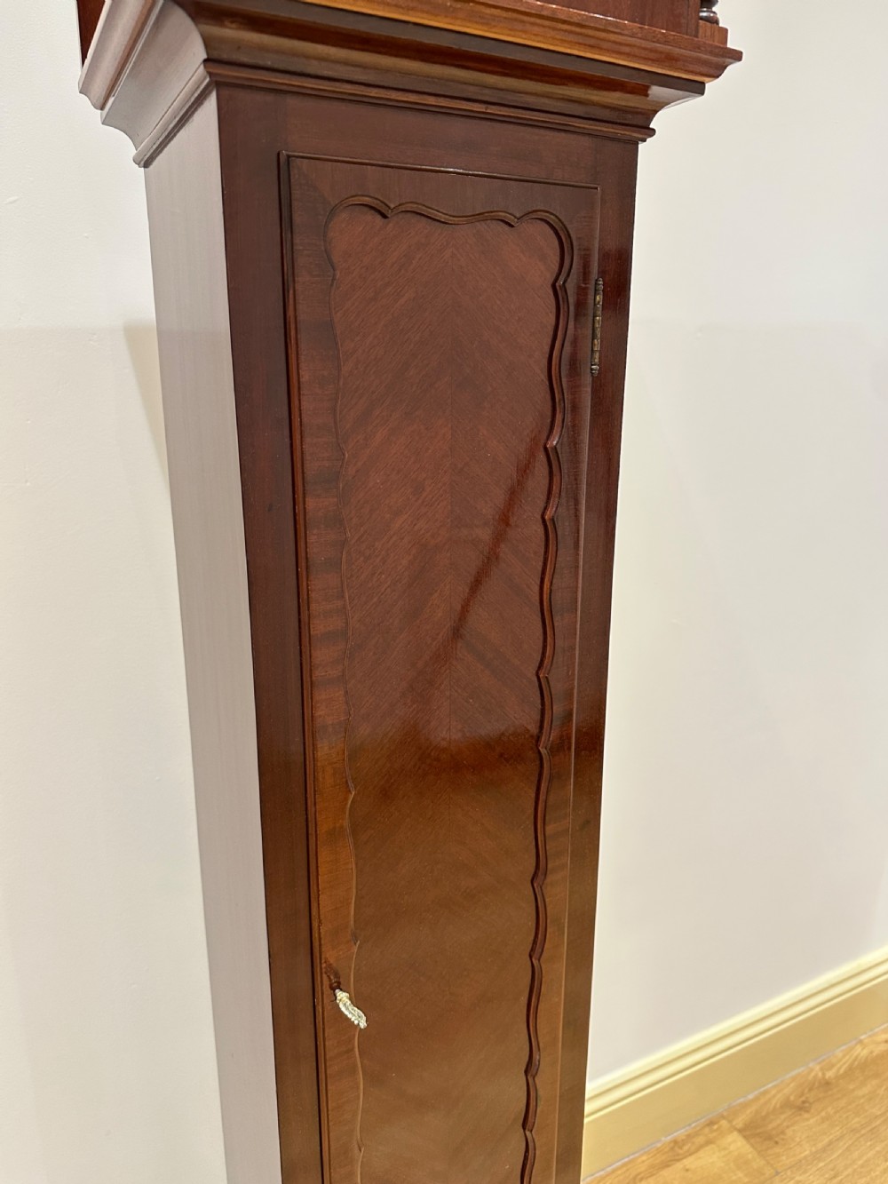 A tall mahogany grandmother clock featuring a brass and silvered dial with Roman numerals, geometric carved mouldings, and bracket feet. View XV