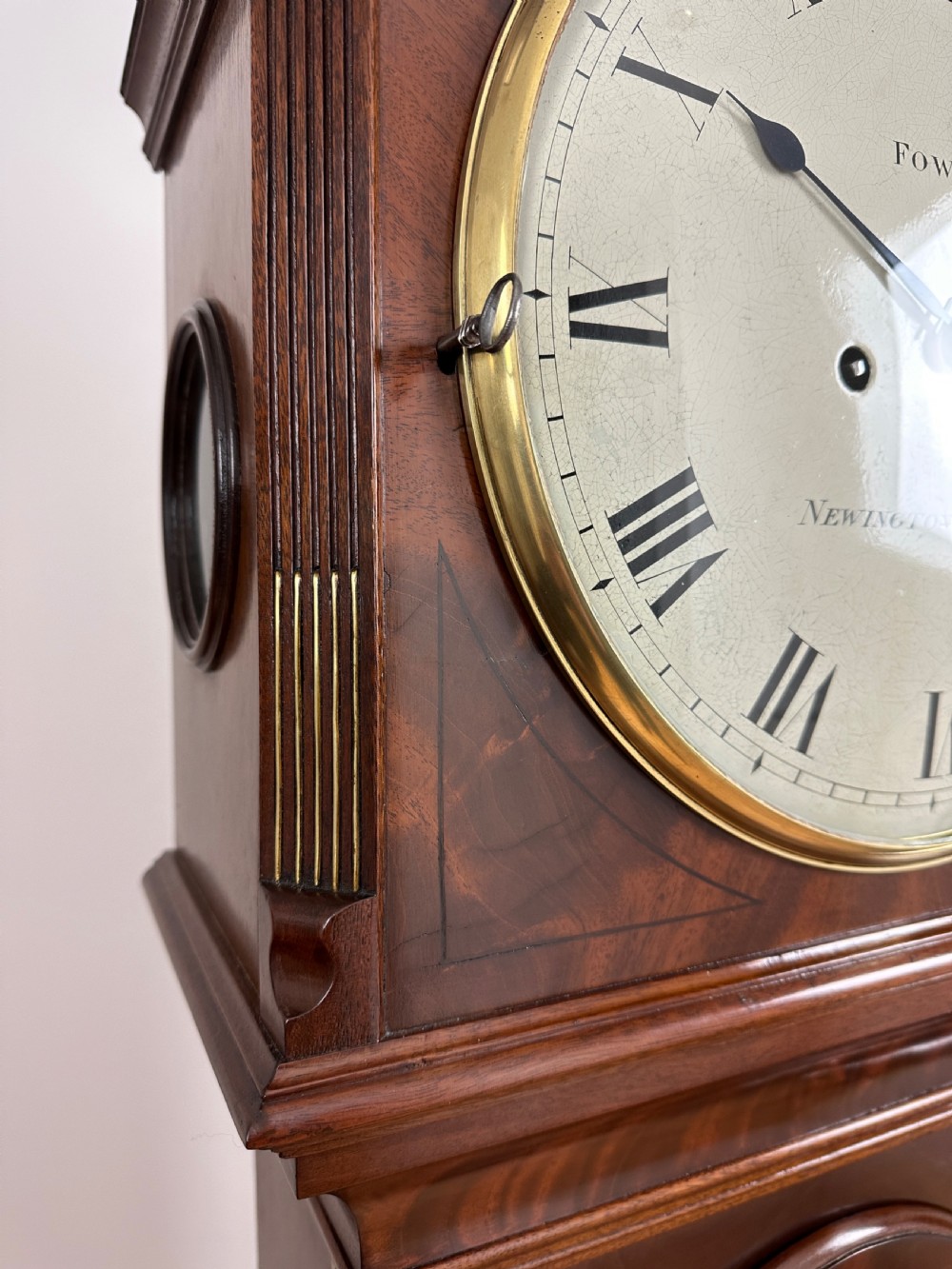 A Georgian tall mahogany longcase clock featuring an arched hood, a circular dial with Roman numerals, and brass fluted quarter columns. View VIII