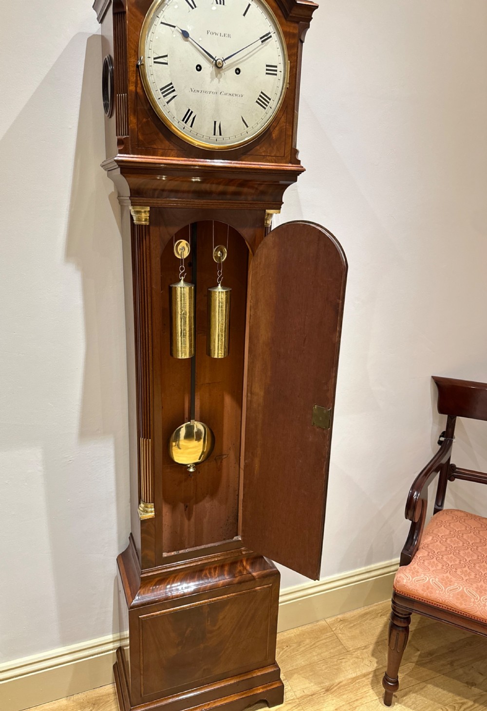 A Georgian tall mahogany longcase clock featuring an arched hood, a circular dial with Roman numerals, and brass fluted quarter columns. View X