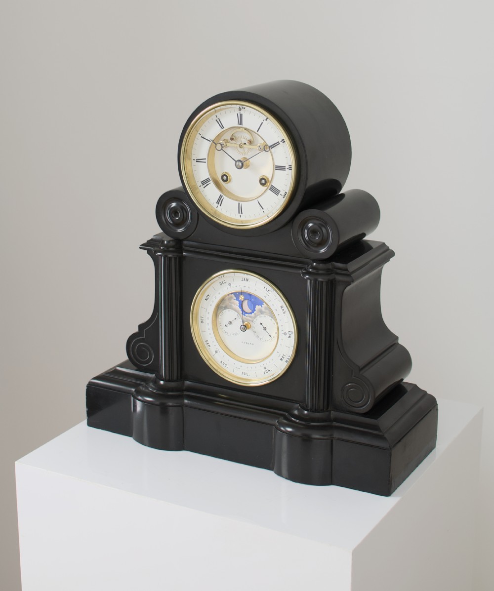 An antique black slate French mantel clock featuring two stacked circular dials, including an upper time display with Roman numerals and a lower perpetual calendar with a moonphase indicator. View III