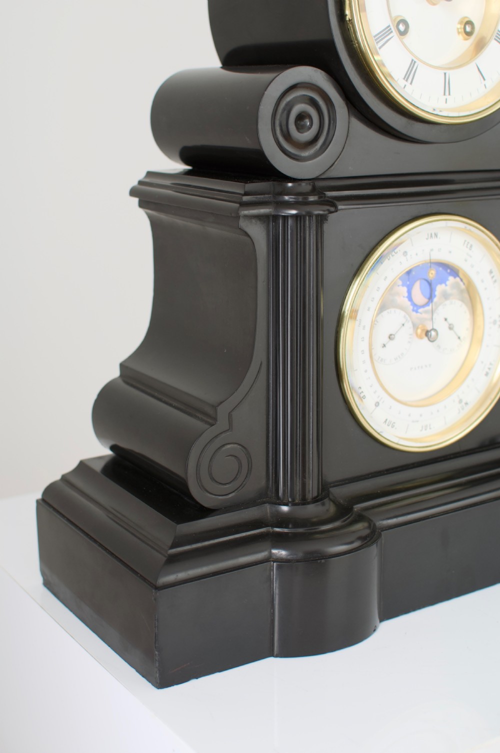 An antique black slate French mantel clock featuring two stacked circular dials, including an upper time display with Roman numerals and a lower perpetual calendar with a moonphase indicator. View XI