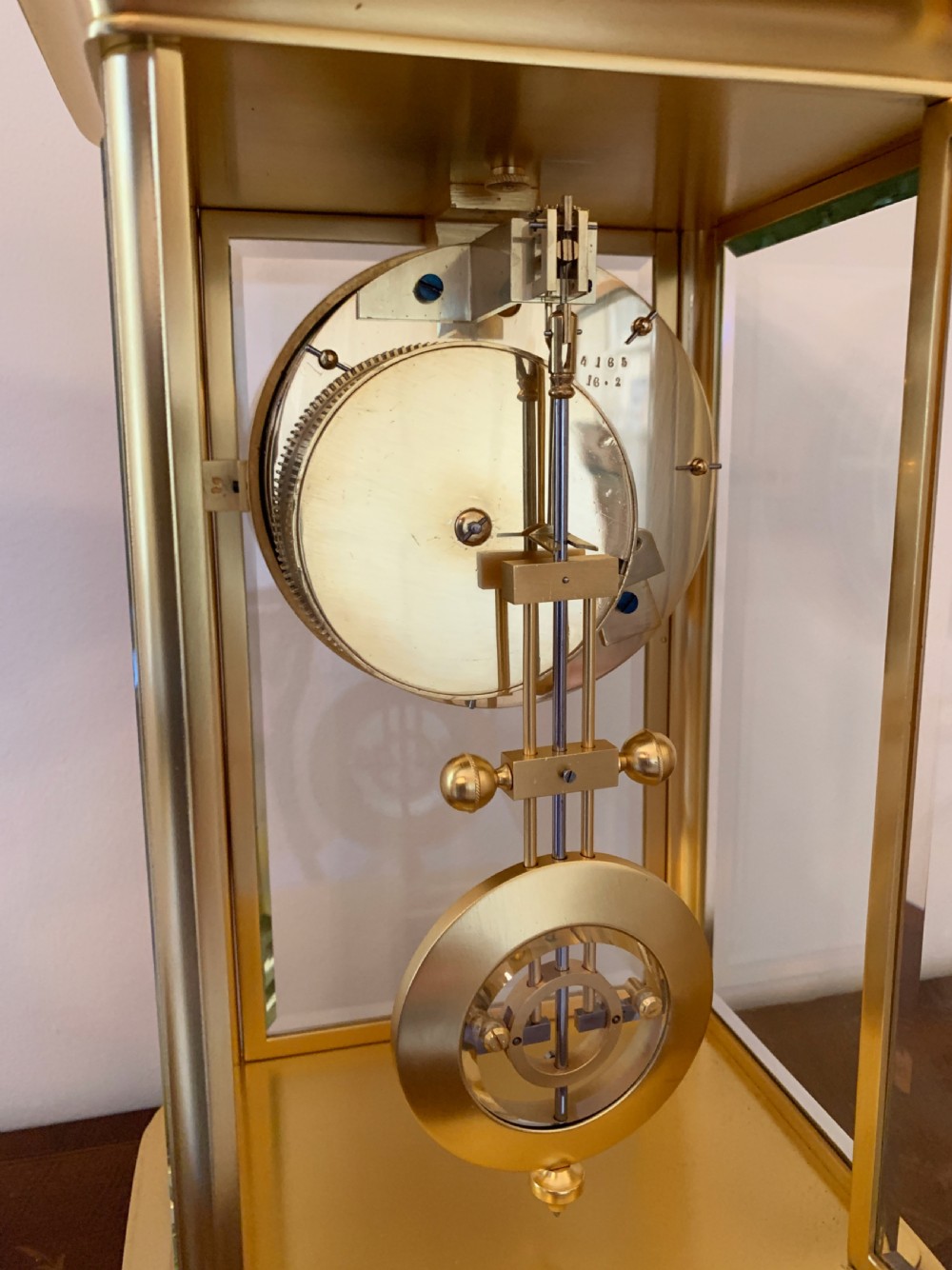 A nineteenth-century French four-glass mantel clock with a gilt brass case, white enamel dial with Roman numerals, exposed Brocot escapement, and visible pendulum. View XII