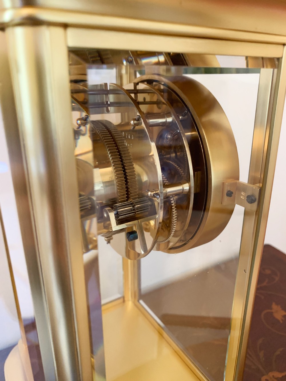 A nineteenth-century French four-glass mantel clock with a gilt brass case, white enamel dial with Roman numerals, exposed Brocot escapement, and visible pendulum. View XV