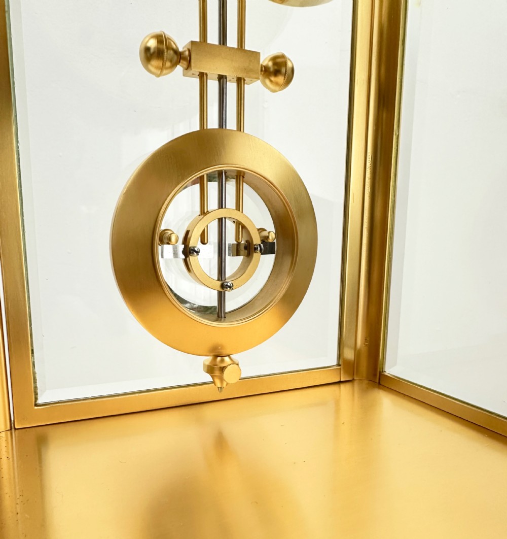 A nineteenth-century French four-glass mantel clock with a gilt brass case, white enamel dial with Roman numerals, exposed Brocot escapement, and visible pendulum. View XVII