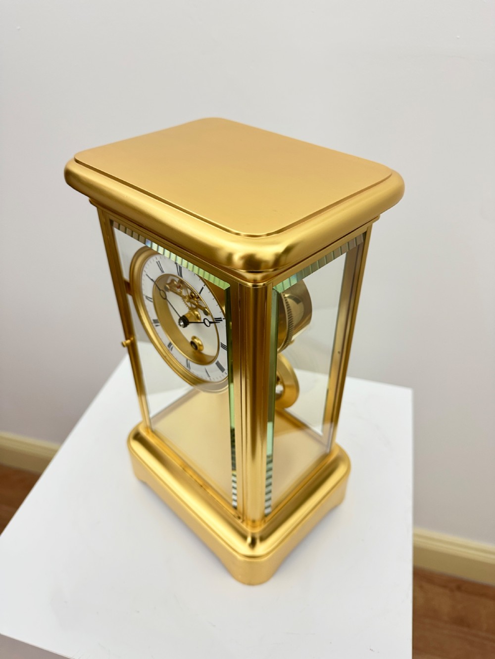 A nineteenth-century French four-glass mantel clock with a gilt brass case, white enamel dial with Roman numerals, exposed Brocot escapement, and visible pendulum. View XVIII