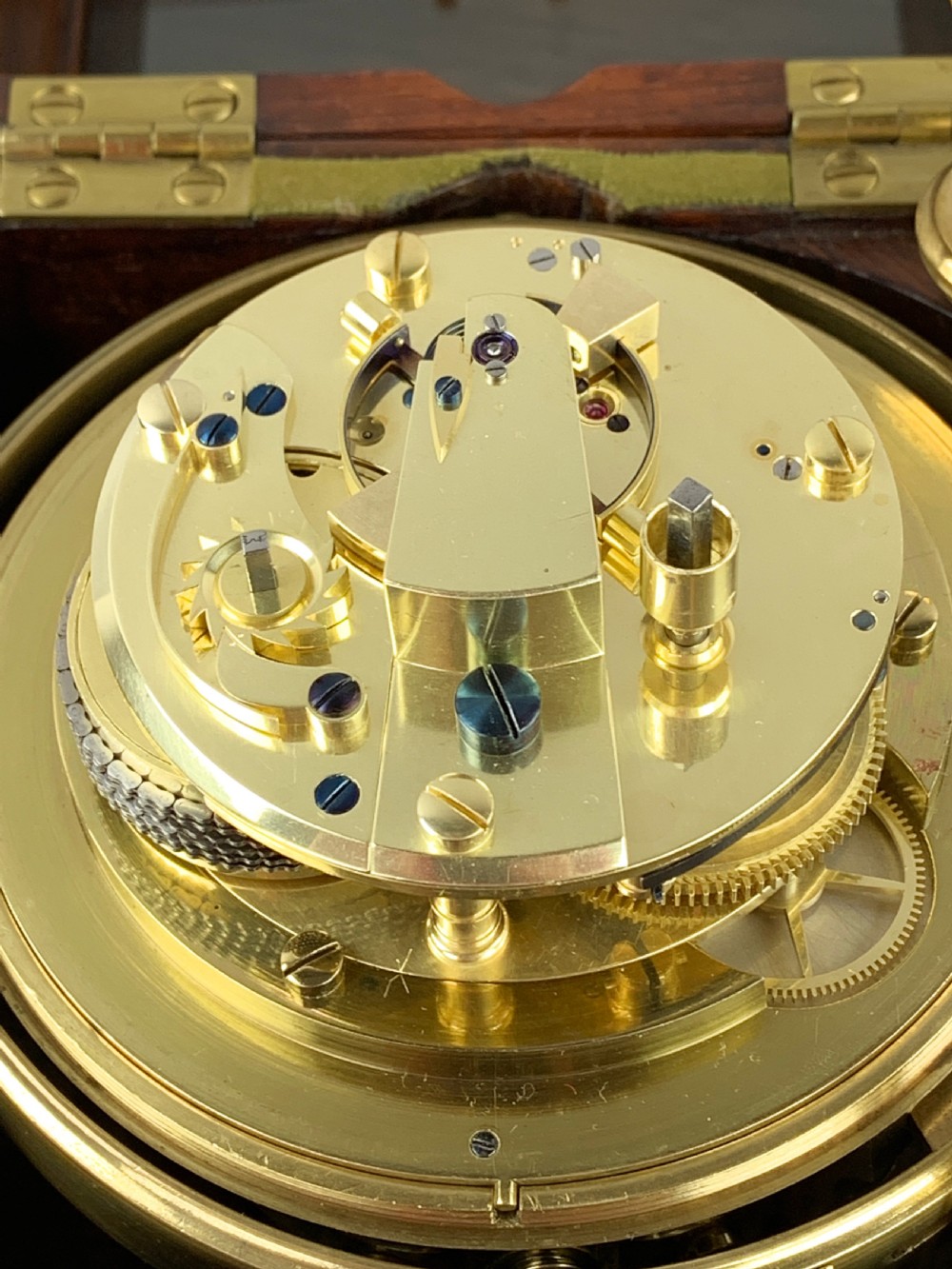 An antique 19th-century brass-bound wooden box opening to reveal a gimballed marine chronometer clock with a silvered dial and Roman numerals. View III
