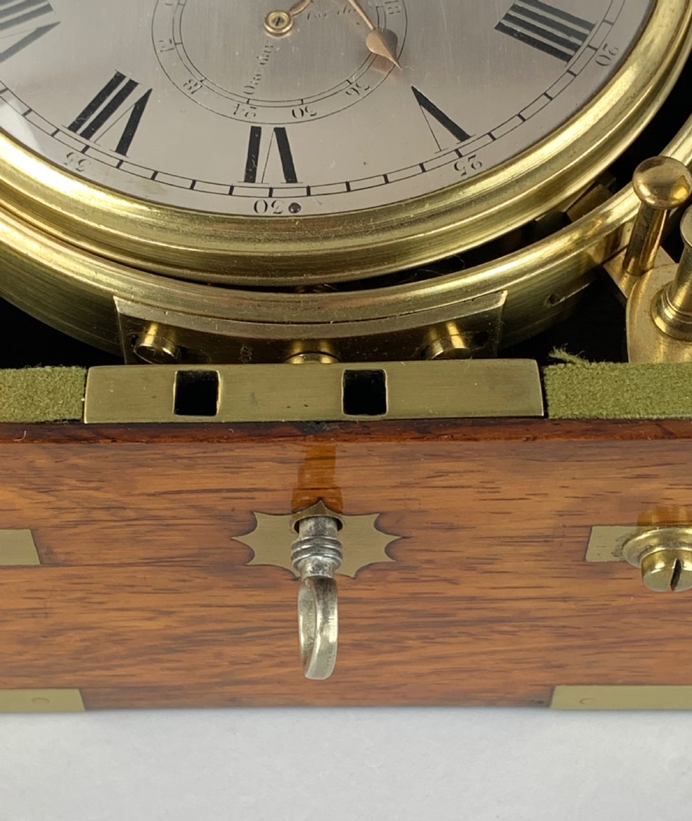 An antique 19th-century brass-bound wooden box opening to reveal a gimballed marine chronometer clock with a silvered dial and Roman numerals. View XIV