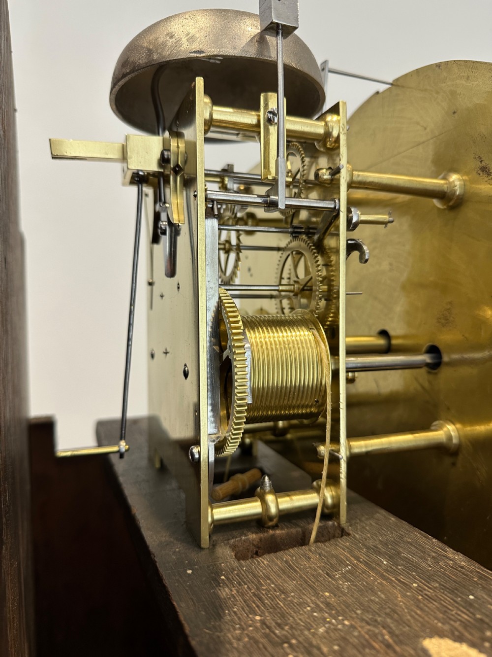 A tall Georgian flame mahogany longcase clock featuring an arched hood, brass finial, and a circular white dial with Roman numerals. View VII