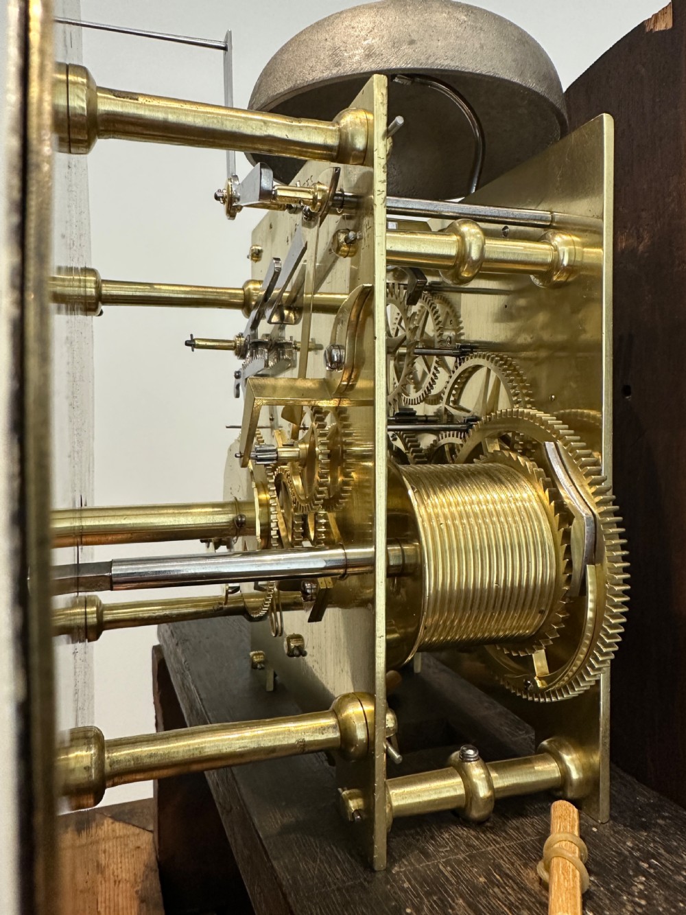 A tall Georgian flame mahogany longcase clock featuring an arched hood, brass finial, and a circular white dial with Roman numerals. View IX