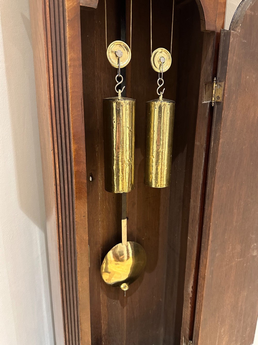 A tall Georgian flame mahogany longcase clock featuring an arched hood, brass finial, and a circular white dial with Roman numerals. View XII