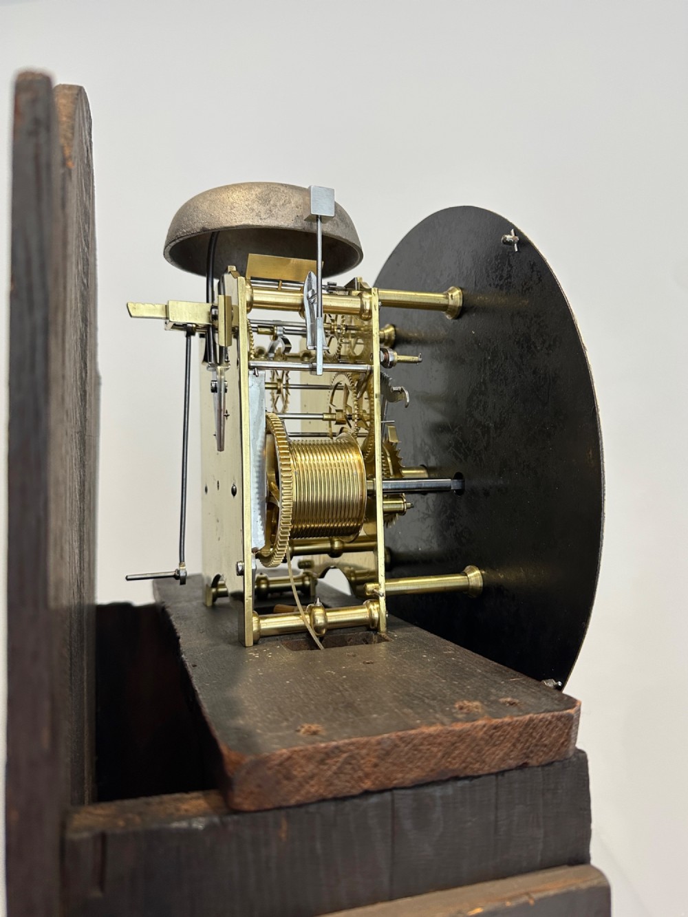 A tall Georgian flame mahogany longcase clock featuring an arched dial hood topped with a brass ball finial, reeded side columns, and a shaped trunk door. View IX