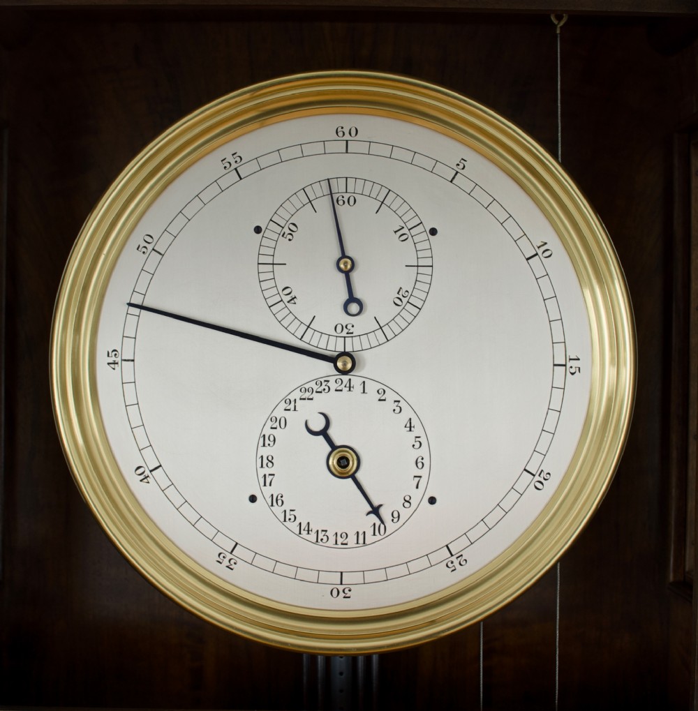 An Edwardian Lenzkirch precision regulator longcase clock housed in a dark walnut case featuring a silvered dial and glazed door revealing a brass pendulum. View II
