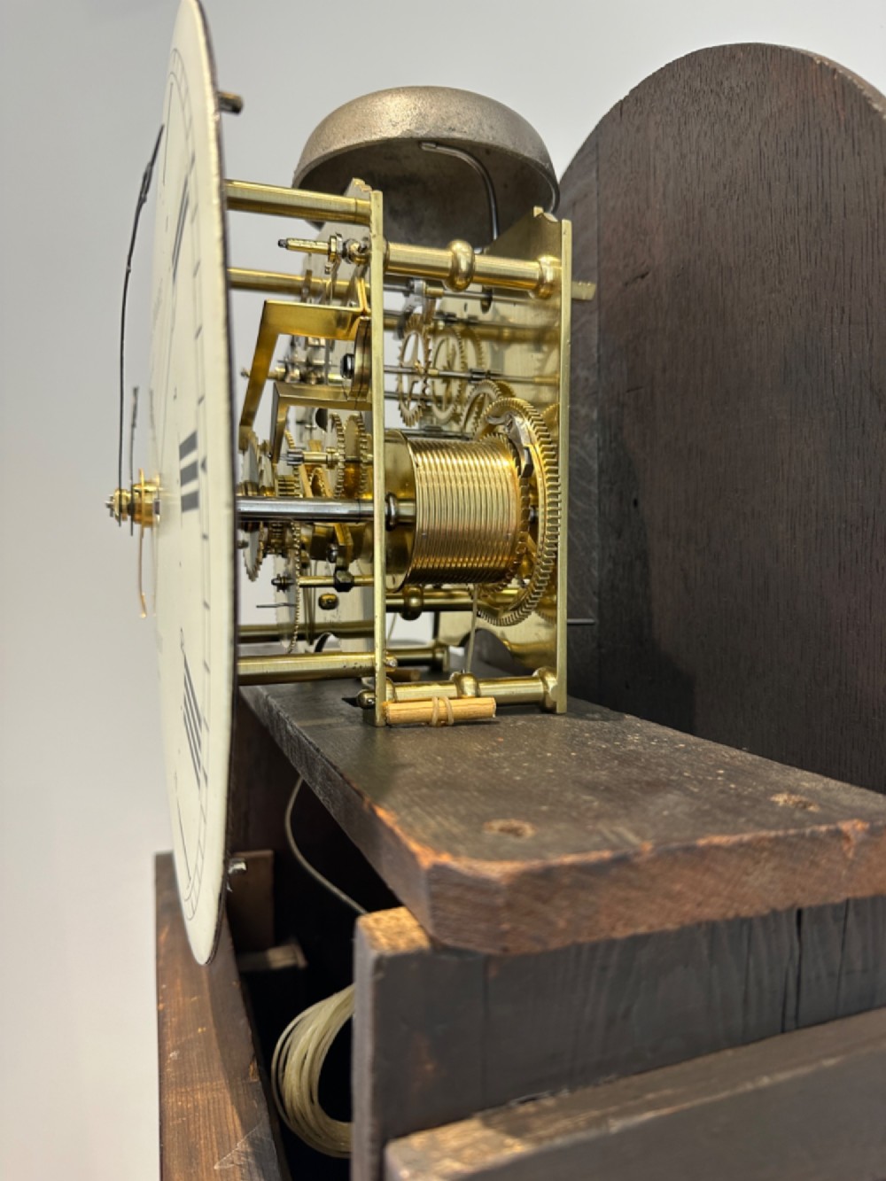 A Georgian flame mahogany longcase clock featuring an arched bonnet top with a brass ball finial, reeded columns, and an enamelled circular dial signed Handley and Moore Clerkenwell London. View XII