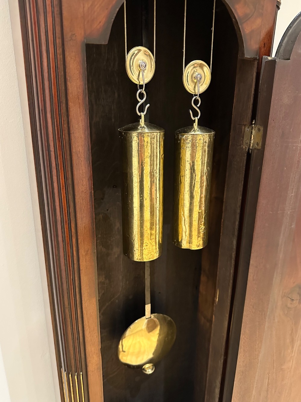 A Georgian flame mahogany longcase clock featuring an arched bonnet top with a brass ball finial, reeded columns, and an enamelled circular dial signed Handley and Moore Clerkenwell London. View XIV