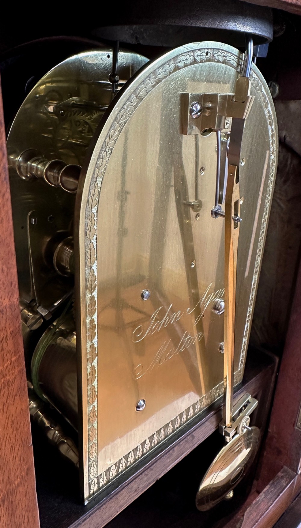 A Georgian mahogany bracket clock featuring a brass pineapple finial, brass side handles, a white dial with Roman numerals, and a lower strike-silent mechanism. View VI