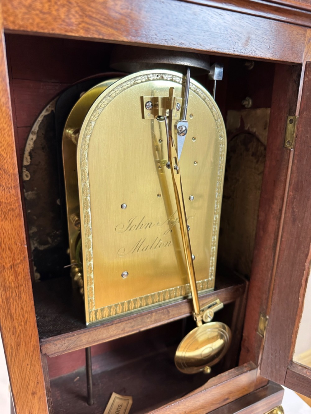 A Georgian mahogany bracket clock featuring a brass pineapple finial, brass side handles, a white dial with Roman numerals, and a lower strike-silent mechanism. View VIII