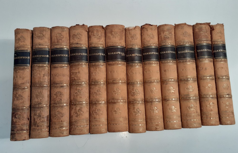 A twelve-volume set of 1856 Shakespeare books bound in tan leather with gilt-tooled floral motifs and black title labels.