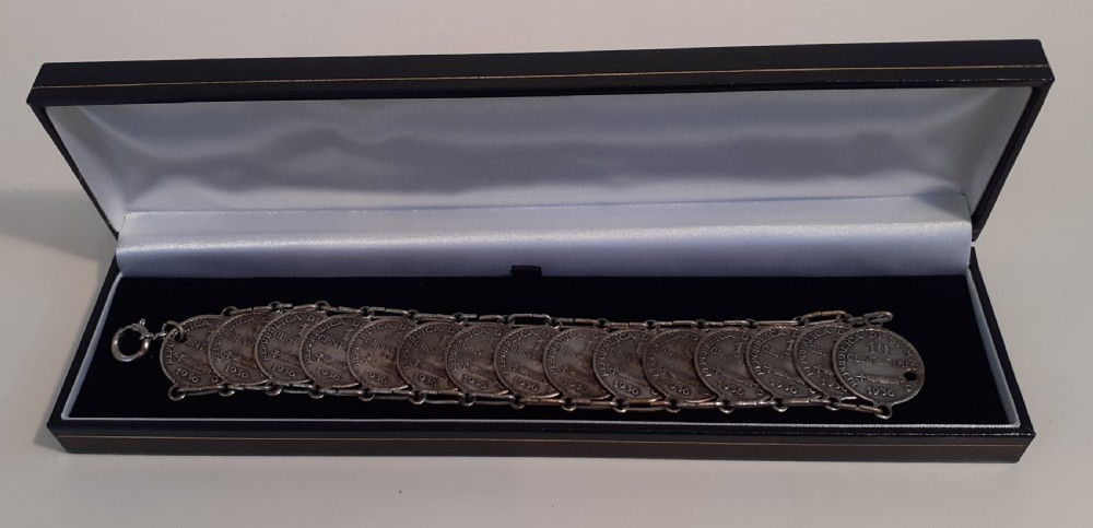 A silver bracelet crafted from fifteen overlapping San Marino ten centesimo coins joined by metal links, resting inside a presentation case. View II