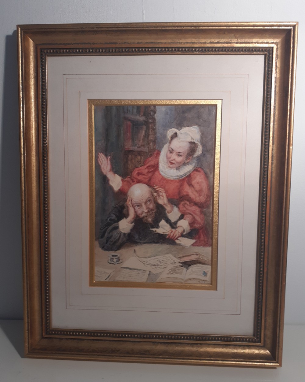 A framed late Victorian watercolour painting depicting William Shakespeare seated at a desk covered with manuscripts while Anne Hathaway stands behind him wearing a red Elizabethan dress.