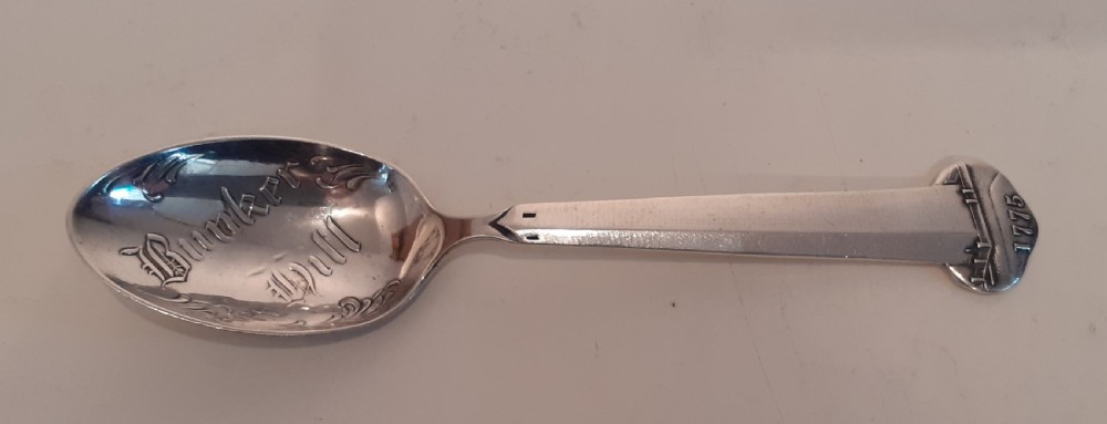 An antique silver souvenir spoon featuring an engraved bowl reading Bunker Hill alongside a handle depicting the Bunker Hill monument and the date 1775.