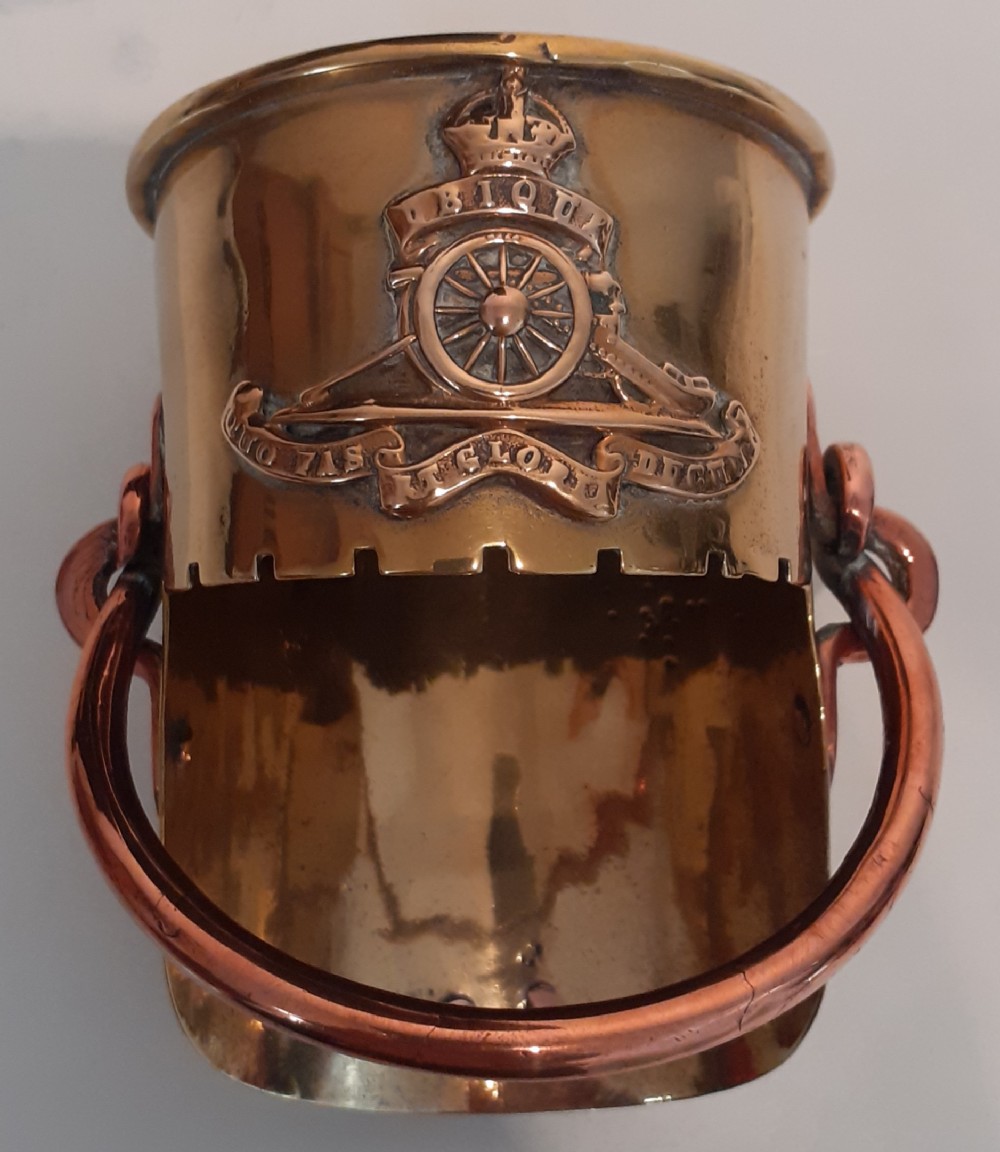 A polished brass First World War trench art vessel fashioned from a shell casing featuring a Royal Artillery crest and copper drop handles.