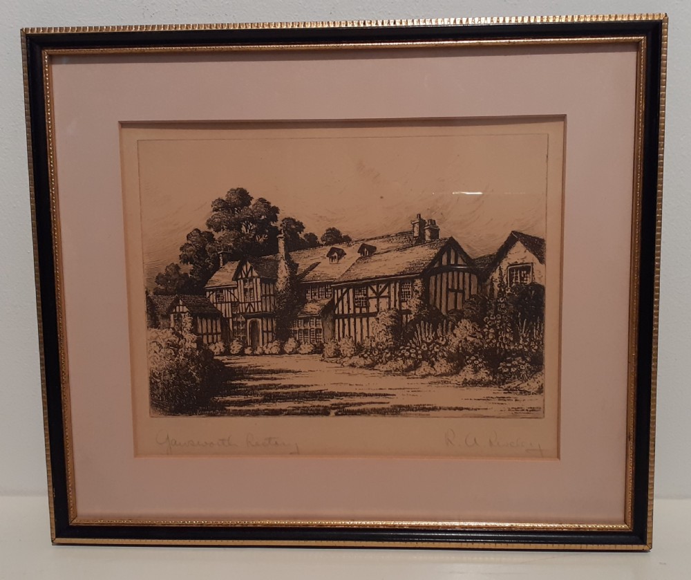 A framed black and white architectural etching depicting a historic half-timbered building, mounted in a black wooden frame with a gold beaded rim.