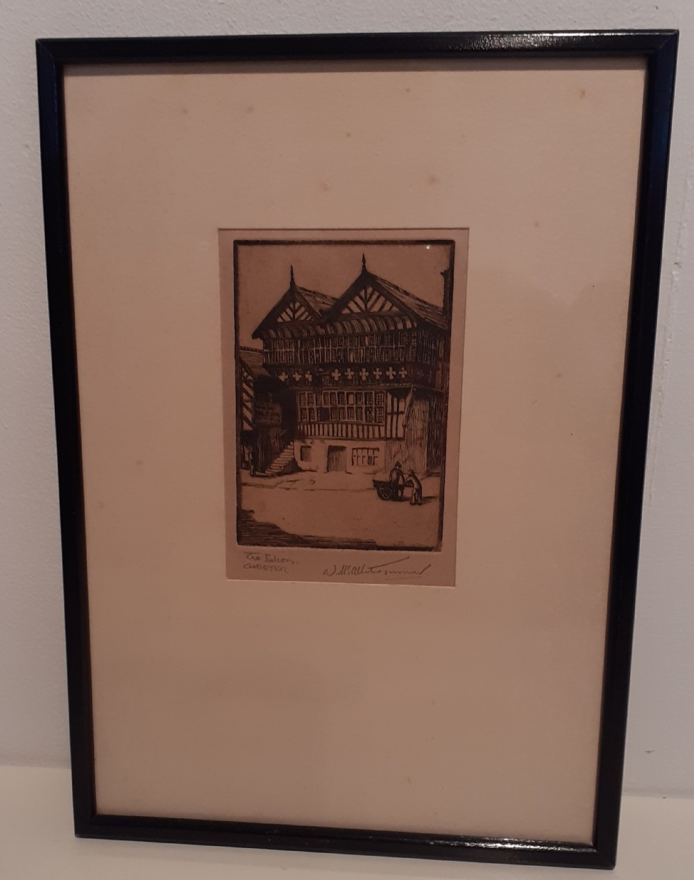 A framed monochrome etching depicting the historic timber-framed Falcon building in Chester, presented within a light cream mount and slim black wooden frame.