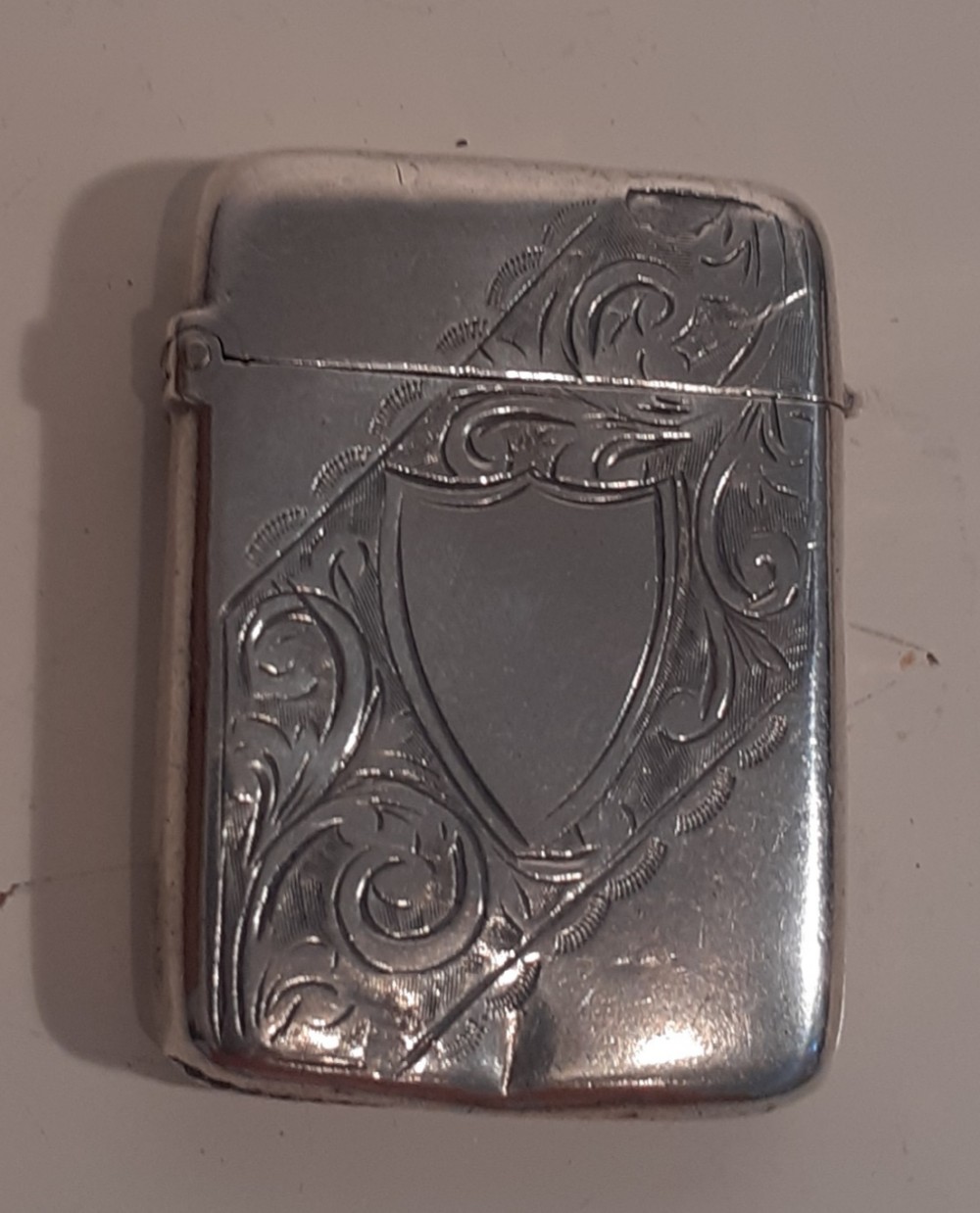 A late Victorian sterling silver vesta case featuring hand-engraved foliate patterns and an unengraved shield cartouche.