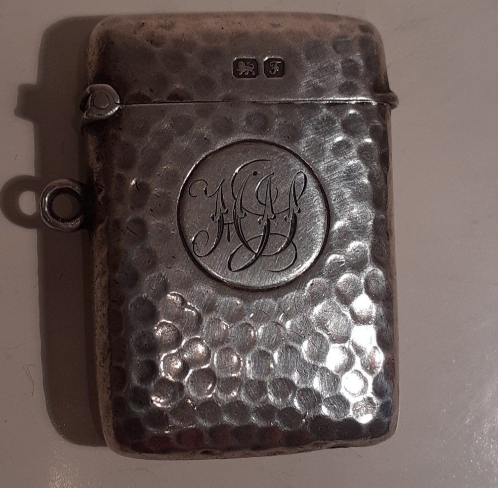 A hammered sterling silver pocket vesta case featuring a central engraved monogram and a side suspension ring.