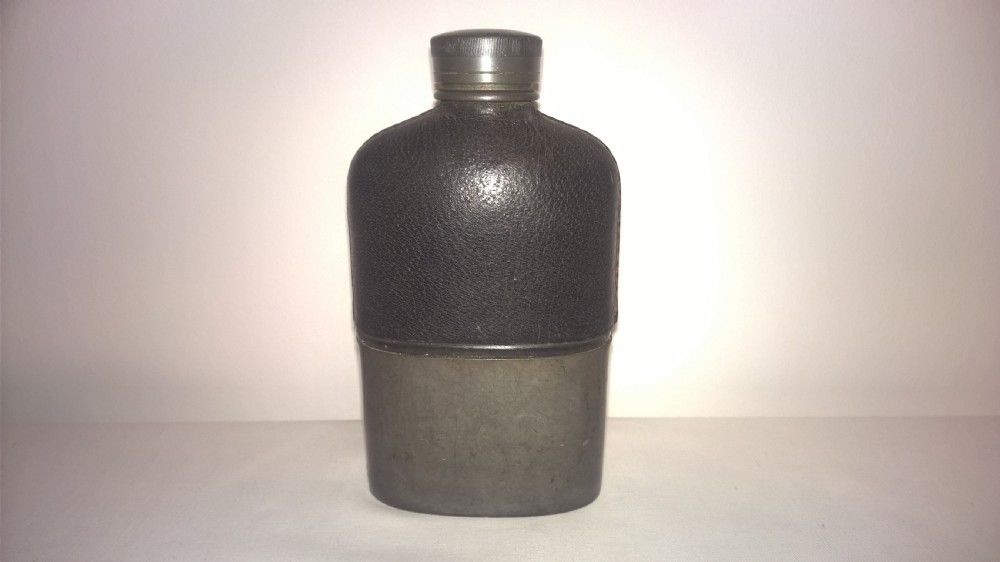 Late nineteenth century pocket hip flask featuring a black leather wrapped upper body and a pewter lower section with a screw top cap. View II
