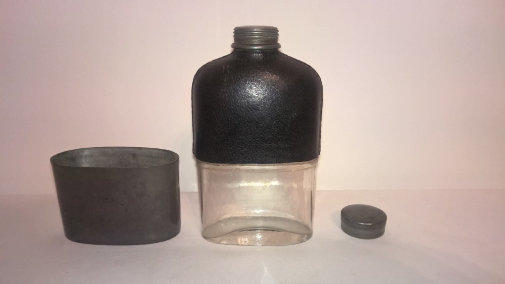 Late nineteenth century pocket hip flask featuring a black leather wrapped upper body and a pewter lower section with a screw top cap. View V