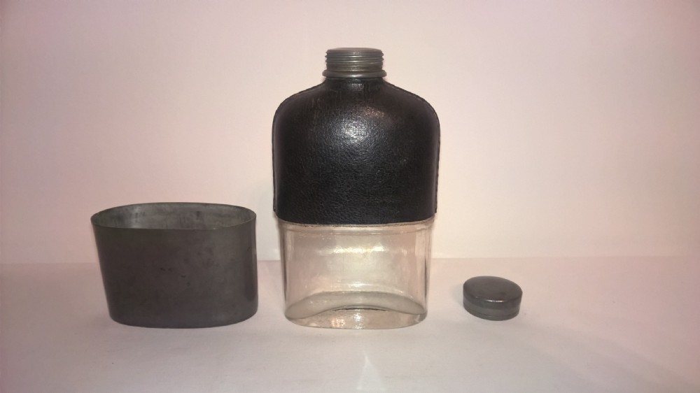 Late nineteenth century pocket hip flask featuring a black leather wrapped upper body and a pewter lower section with a screw top cap. View VI
