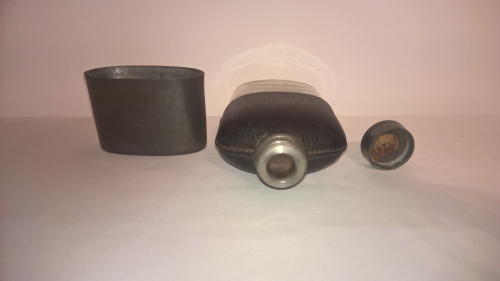 Late nineteenth century pocket hip flask featuring a black leather wrapped upper body and a pewter lower section with a screw top cap. View VII