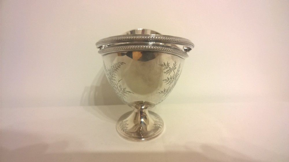 An 1877 hallmarked sterling silver pedestal sweet basket featuring an overhead handle, beaded trim, and engraved botanical motifs. View III