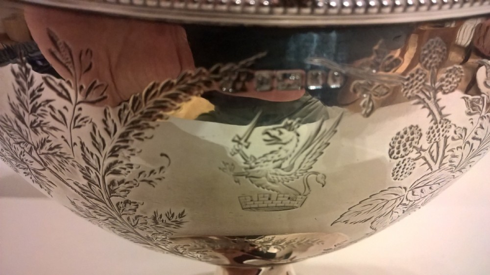 An 1877 hallmarked sterling silver pedestal sweet basket featuring an overhead handle, beaded trim, and engraved botanical motifs. View VI