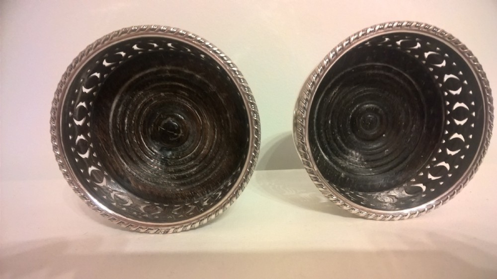 A pair of circular silver-plated wine coasters featuring pierced gallery sides, beaded borders, and turned hardwood bases. View II
