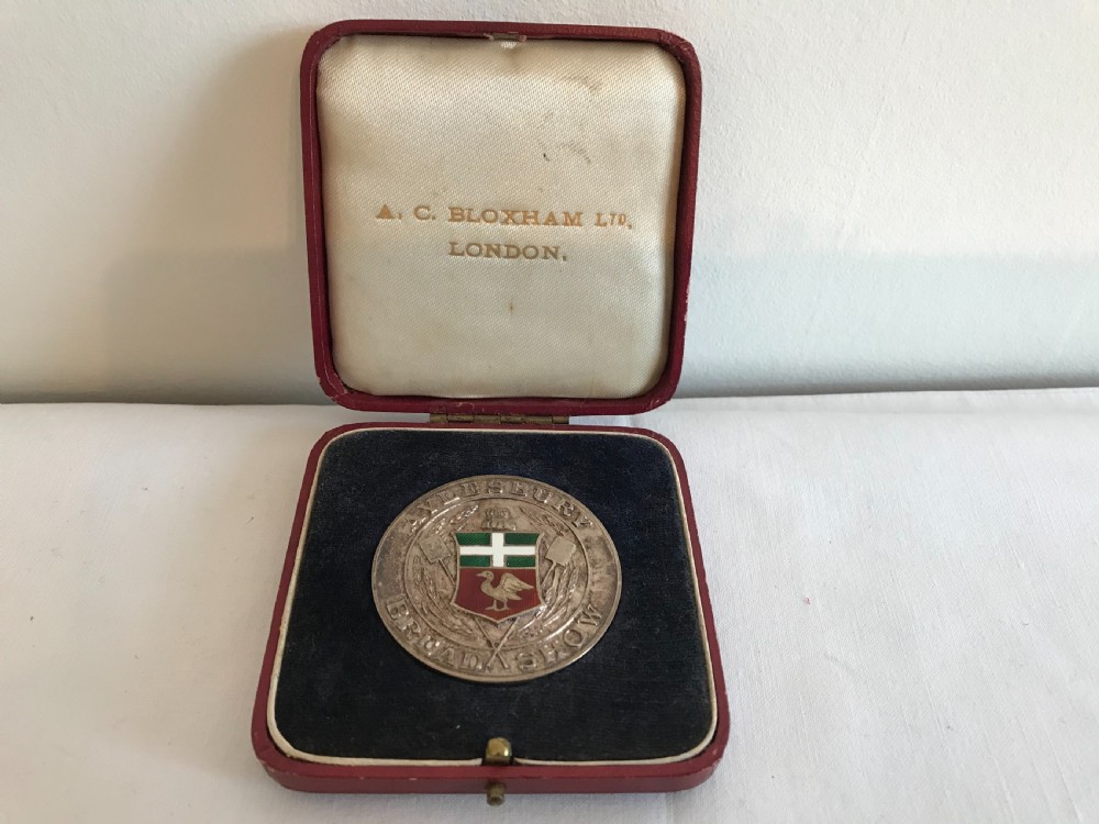 A circular 1935 silver prize medal with a central enamel shield detailing, resting inside an open red velvet-lined presentation box.