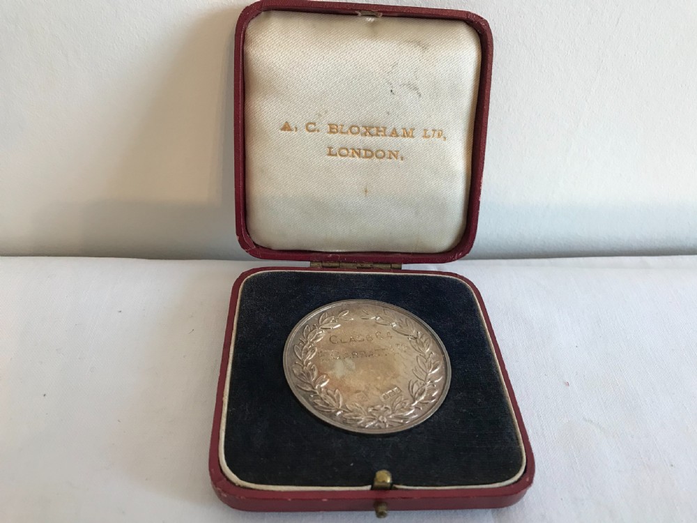 A circular 1935 silver prize medal with a central enamel shield detailing, resting inside an open red velvet-lined presentation box. View II